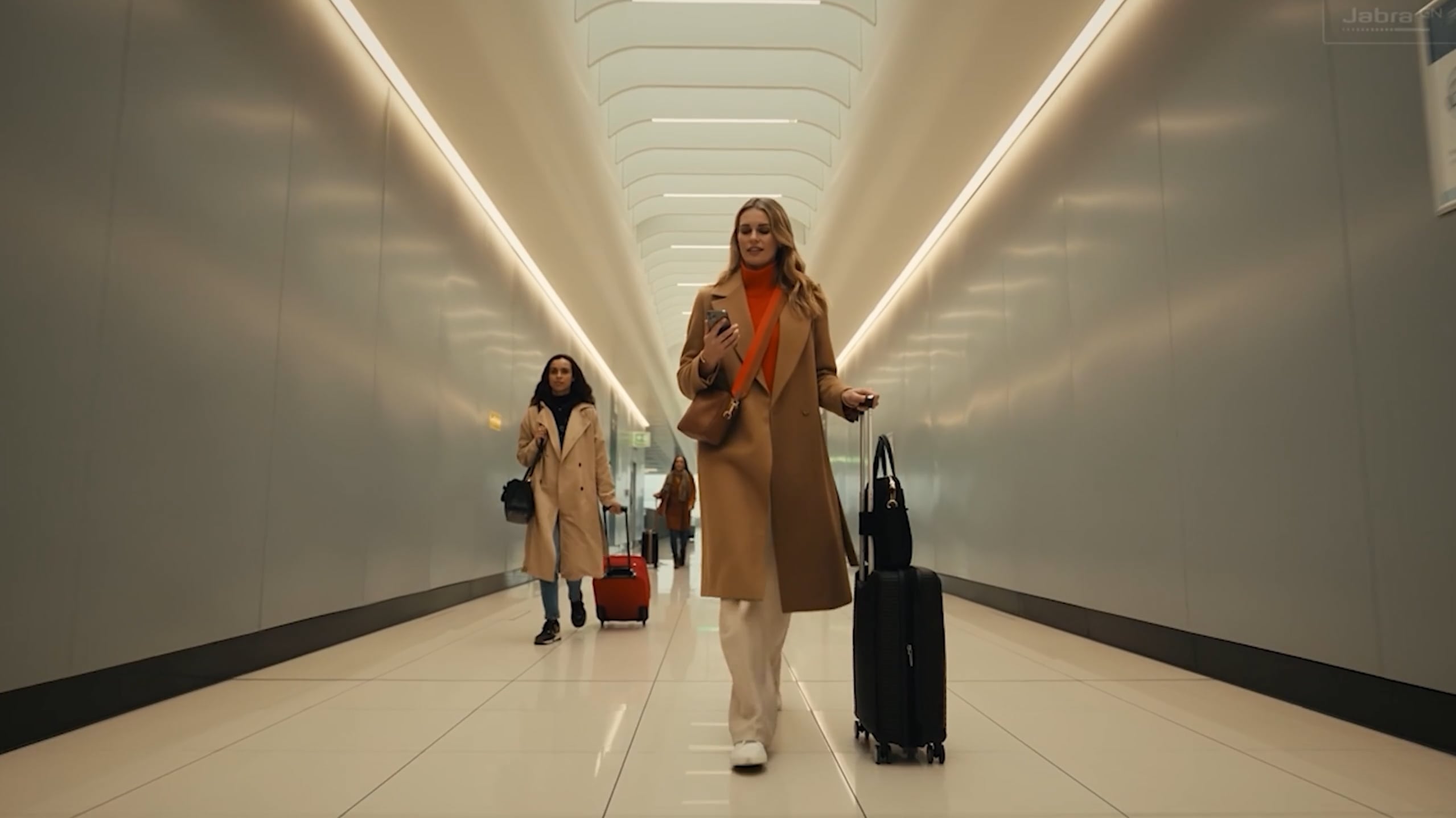 Frame from the Jabra broadcast ad: two travellers walking a bright airport corridor with luggage, Jabra GN watermark in the corner.